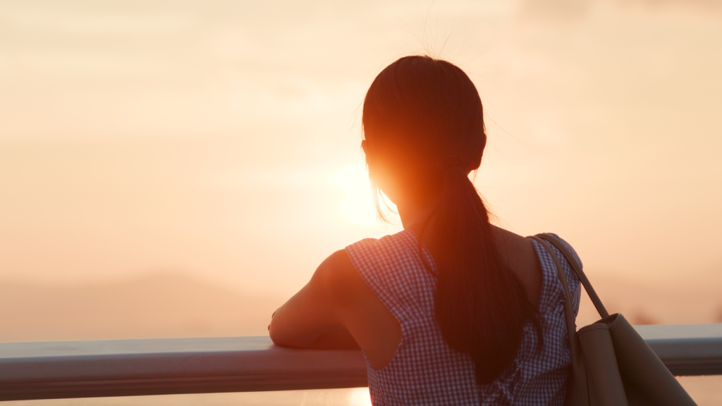 Woman enjoying a sunset view on a balcony.