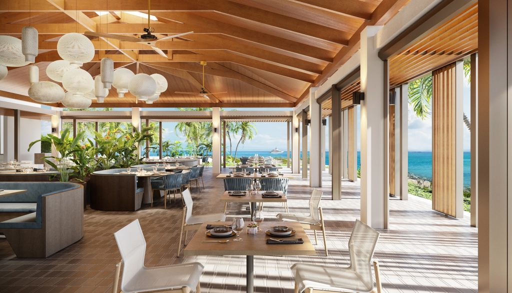 Open-air restaurant with modern decor, set tables, and a view of the ocean, palm trees, and clear blue sky.