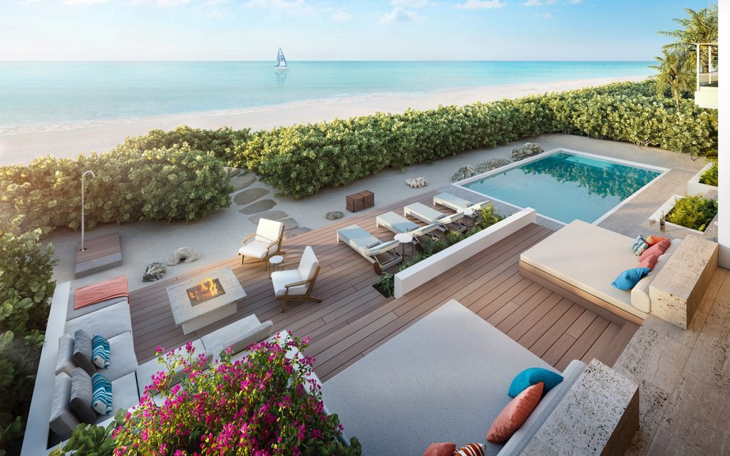 Modern beachfront patio with pool, lounge chairs, fire pit, and ocean view; sailboat visible in the distance.